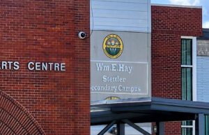 Wm. E. Hay & Stettler Elementary Remain Open Under RCMP Presence Exterior view of a brick Arts Centre building with a round school logo and sign reading 'Wm. Hay Stettler Secondary Campus' (front entrance area).