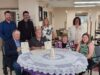 Stettler Town and County Partner for 40th Annual Seniors Week Celebrations Group of eight adults posing around a round table, some holding certificates and smiling in a bright, indoor room.