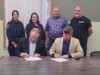 Town of Stettler & County of Stettler Declare May 25-29 As Alberta Rural Health Week Two men seated at a long table sign documents while four colleagues stand behind them in a meeting room.