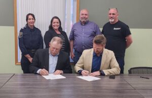 Town of Stettler & County of Stettler Declare May 25-29 As Alberta Rural Health Week Two men seated at a long table sign documents while four colleagues stand behind them in a meeting room.