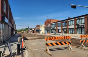 Stettler Residents Encouraged To Visit Businesses Impacted By Construction Street under construction with orange barriers reading 'ROAD CLOSED' and a closed curbside area on a sunny day in a commercial district.