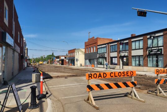 Stettler Residents Encouraged To Visit Businesses Impacted By Construction Street under construction with orange barriers reading 'ROAD CLOSED' and a closed curbside area on a sunny day in a commercial district.
