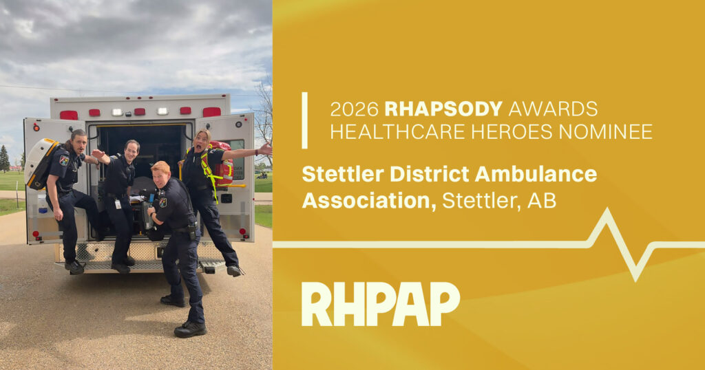 Four paramedics jump from the open rear of an ambulance, with a gold RHAPSODY Awards banner announcing the 2026 Healthcare Heroes nominee: Stettler District Ambulance Association, Stettler, AB.