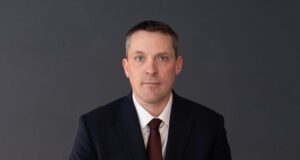 Drumheller-Stettler UCP MLA Nate Horner Not Seeking Re-Election Professional headshot of a man in a navy suit and burgundy tie against a dark gray background.