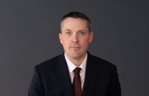 Drumheller-Stettler UCP MLA Nate Horner Not Seeking Re-Election Professional headshot of a man in a navy suit and burgundy tie against a dark gray background.