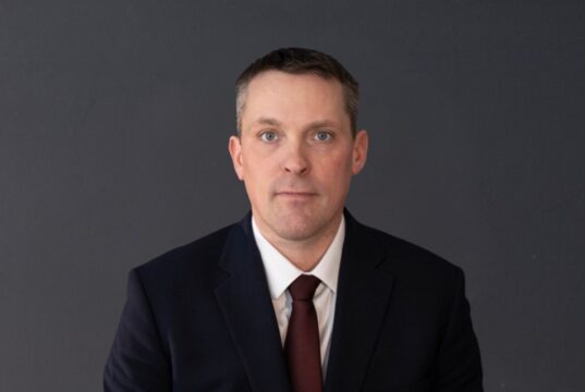 Drumheller-Stettler UCP MLA Nate Horner Not Seeking Re-Election Professional headshot of a man in a navy suit and burgundy tie against a dark gray background.