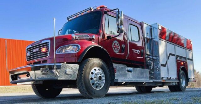 Front-left view of a red fire engine with chrome bumper and diamond-plate detailing, parked outdoors.