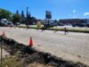 Stettler Back-to-School Traffic: 50 Ave Construction & Detour Map Construction work on a city street with orange cones and red barricades; a deep trench runs along the road and a large cement mixer truck is parked nearby, with buildings and trees in the background.