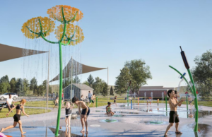 Stettler Spray Park Upgrade to Direct Recycled Water to Local Golf Course Children playing on a splash pad with yellow flower water jets under a blue sky.