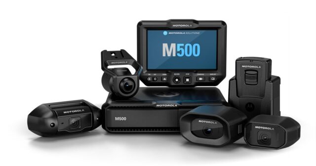 m500-social-thumb Motorola M500 action camera bundle with central display monitor and several wearable cameras and accessories arranged on a white backdrop.