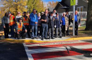 Town of Stettler and Legion Branch Dedicate Veterans Crosswalk Group photo of veterans in blazers with medals and workers in orange safety vests posing on a sidewalk in fall colors.