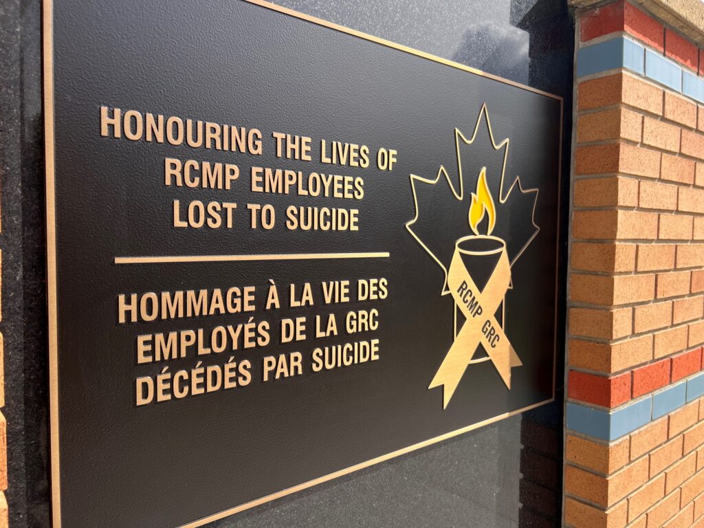 Plaque honoring RCMP employees who died by suicide, with a maple-leaf emblem and flame imagery.