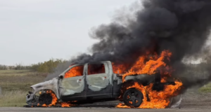 Heartland Regional Fire Extinguishes Highway 835 Vehicle Blaze A burned pickup truck on a rural road engulfed in bright orange flames with thick black smoke.