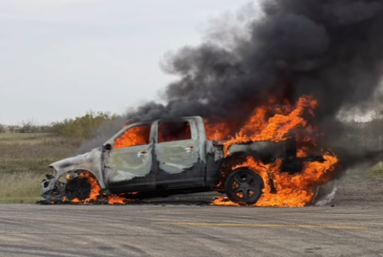 Heartland Regional Fire Extinguishes Highway 835 Vehicle Blaze A burned pickup truck on a rural road engulfed in bright orange flames with thick black smoke.