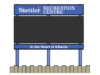 Town of Stettler Awards $68K Contract For New Recreation Centre Digital Sign Outdoor sign for Stettler Recreation Centre, with a blue header and posts, showing the slogan 'In the Heart of Alberta' on a wooden fence backdrop.