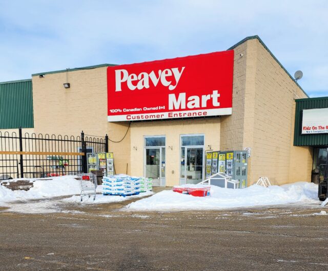 Peavey Mart storefront on a beige brick building with a large red sign, snow in the parking lot in front.