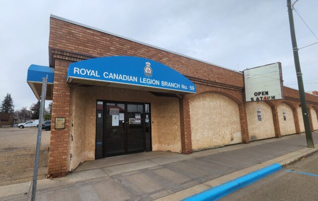 20261019_124839 Brick building storefront with a blue curved sign reading 'ROYAL CANADIAN LEGION BRANCH No. 59' above the entrance.