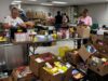 Stettler & District Food Bank Drive Raises Over $10K In Donations Volunteers sorting and packing canned goods and boxed foods at a busy food pantry workstation.