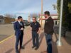 Pierre Poilievre: The Best Of Canada Answered The Call In Wainwright Three men stand on a brick sidewalk in a small‑town street, conversing: a man in a navy suit, a police officer, and a casually dressed man.