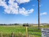 Town of Stettler Awards Lagoon Desludging Project Rural scene with a tall wooden utility pole beside a gate and a sign reading 'Town of Stettler Sewage Lagoons No Trespassing No Dumping' against a blue sky and grassy field.