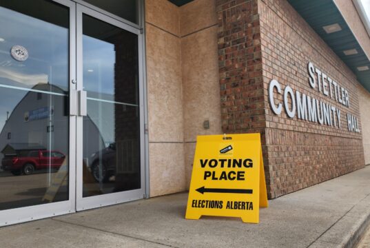 How to Vote In The 2026 Alberta Referendum Exterior view of a brick community hall with a bright yellow